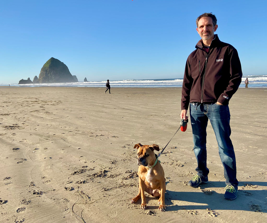 Brian Nelson stands on a beach with dog